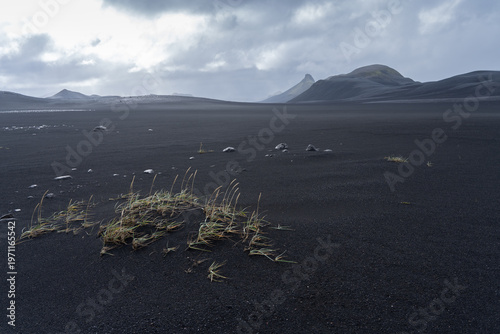 Volcanic landscape with black sand, mountains in the backdrop and cloudy sky, Iceland