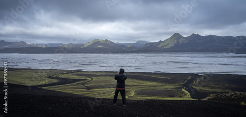 Man standing in front of vast glacial landscape with mountains and glacial river, Iceland