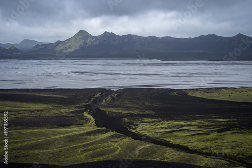 Mountainous volcanic landscape with huge glacial river and heavy clouds above, Iceland