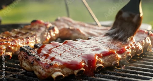 Ribs being brushed with barbecue sauce.