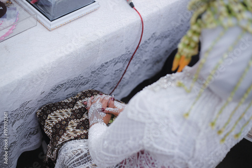 Photography Traditional Indonesian bride's hands adorned with white henna during ceremony