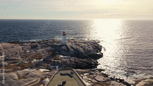 Cinematic Drone Shot High drone aerial golden sunset: Peggy's Cove lighthouse and snowy shore along Atlantic near Halifax. Nova Scotia Canada winter landscape, peaceful coastal view 4K.