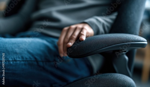 An office worker's hand gripping the fabric-covered armrest of an ergonomic office chair