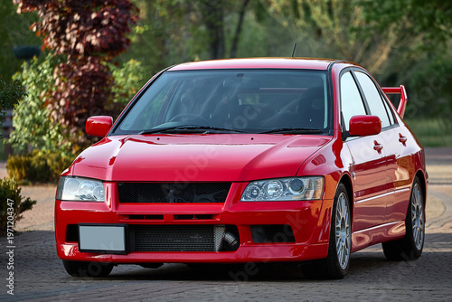 Red car on the street, sports sedan parked on an empty road with guardrails in daylight, no people