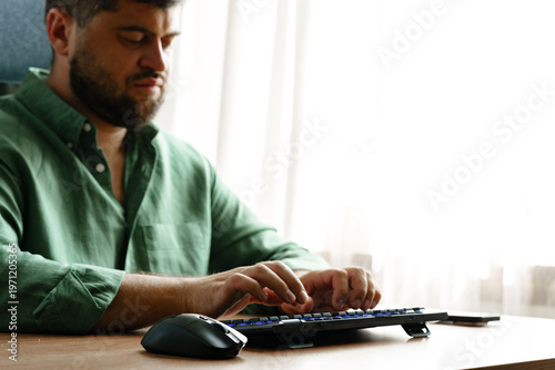 Canvastavla Man typing on keyboard while sitting at desk by window in a well-lit room