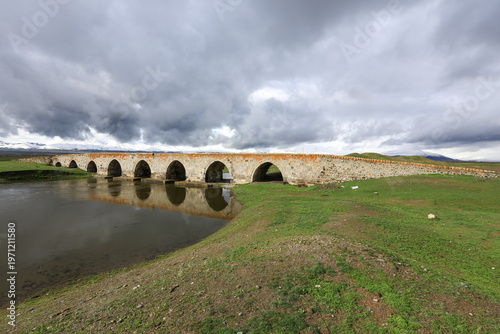 A image of a multi-arched stone bridge built over a wide riverbed.