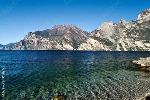 Crystal clear shoreline of Lake Garda with dramatic limestone cliffs