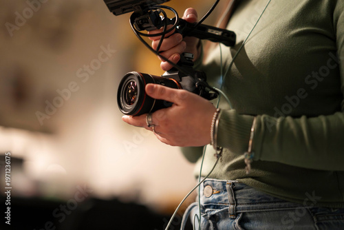 A person holds a camera with a microphone attached, preparing to film.