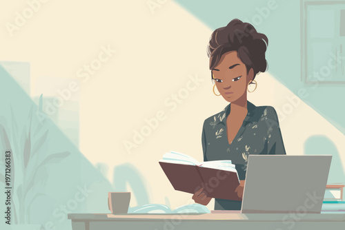 African female young adult reading book at desk with laptop in sunlit room