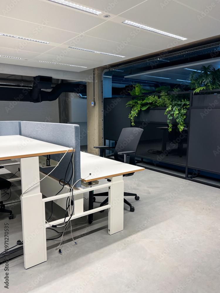 Fototapeta premium An open-plan contemporary office layout incorporates a lush greenery zone with potted plants and vertical garden, creating a calm and productive atmosphere. Startup workspace inspiration, HR wellness