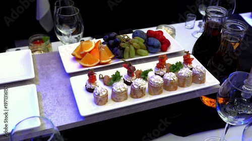 Cream cheese rolls, fresh fruits, and wine adorning white plates showcase sophisticated dining experience at elegant catering event