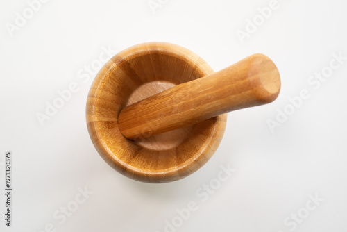 Top-down close-up of a wooden mortar and pestle on white background