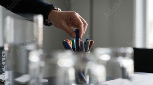 Individual's hand holding a pencil with intent to write or draw in a creative workspace indicating artistic expression