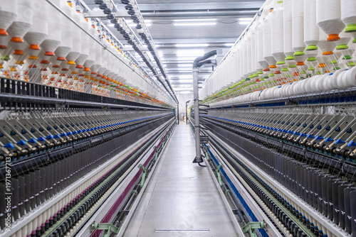 Fotografía Balanced composition of spinning machines aligned in a textile factory corridor with central piping infrastructure