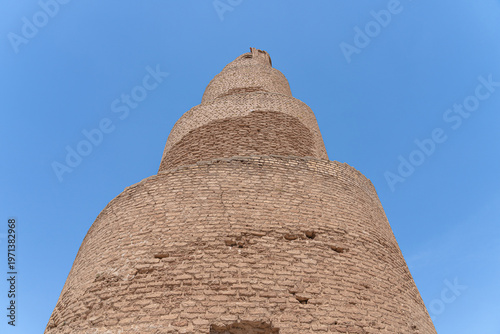A striking minaret, built with layered brickwork, commands attention against the vibrant blue sky in Abu Dulaf, Iraq