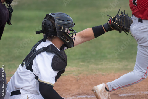 Young high School baseball catcher with the ball in his glove and the batter swinging