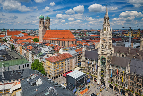 Detailed aerial perspective of the Neues Rathaus tower and the iconic Frauenkirche cathedral against a blue sky in Munich, Bavaria, Germany.