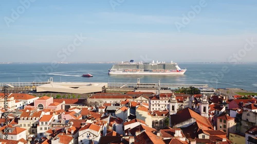 Alfama Historic Neighborhood and Big Cruise Ship Leaving Port on Sunny Day. Red Roofs and White Houses. Vibrant Lisbon Old Town, Portugal. View from Miradouro das Portas do Sol