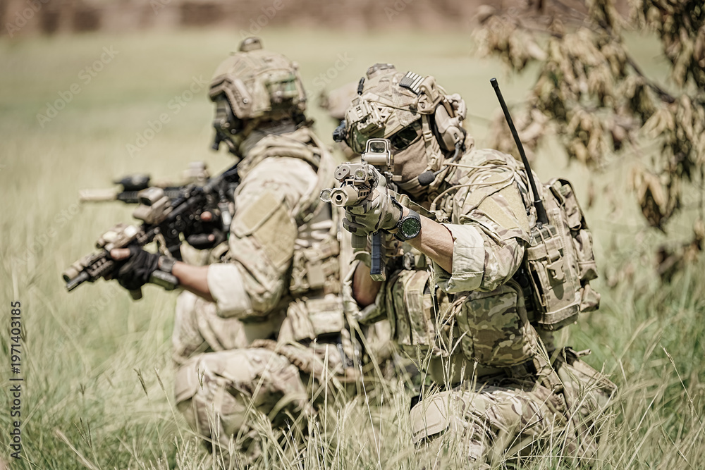 Fototapeta premium Special forces soldiers in camouflage gear advance cautiously through tall grass