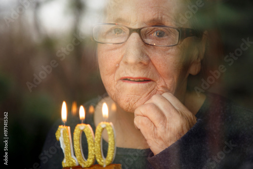 фотографія Portrait of an elderly woman with glasses holding anniversary candles
