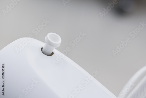 A white plastic pull-knob for controlling fan oscillation.