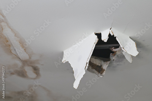 Damaged ceiling with water stains and a large hole.
