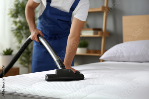 Man cleans mattress with vacuum in tidy bedroom