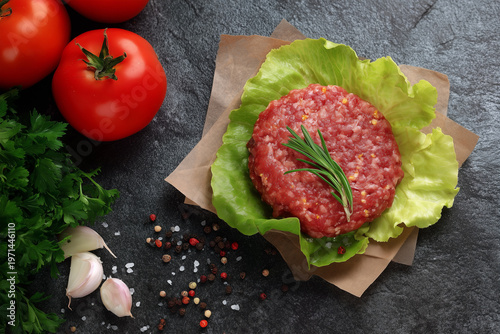Fresh ground meat with vegetables on a dark stone surface