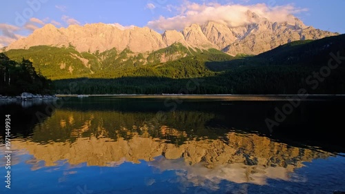 Stunning landscape video of the sunset over Eibsee lake with clear mountain reflections and the Zugspitze massif in the Bavarian Alps, Germany.