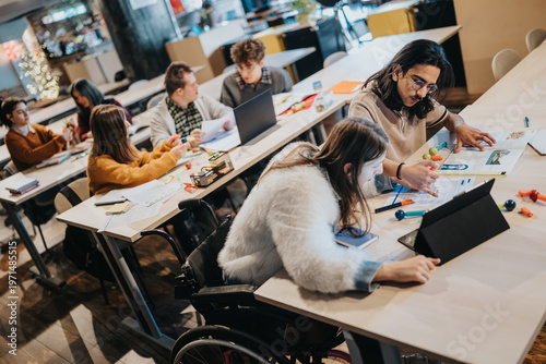 Quadro su tela A diverse group of college students studying and collaborating at long tables in a classroom