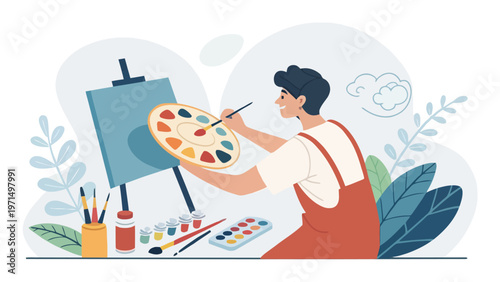 Male artist mixing colors on palette while painting on canvas with brushes and paints around him in a creative studio