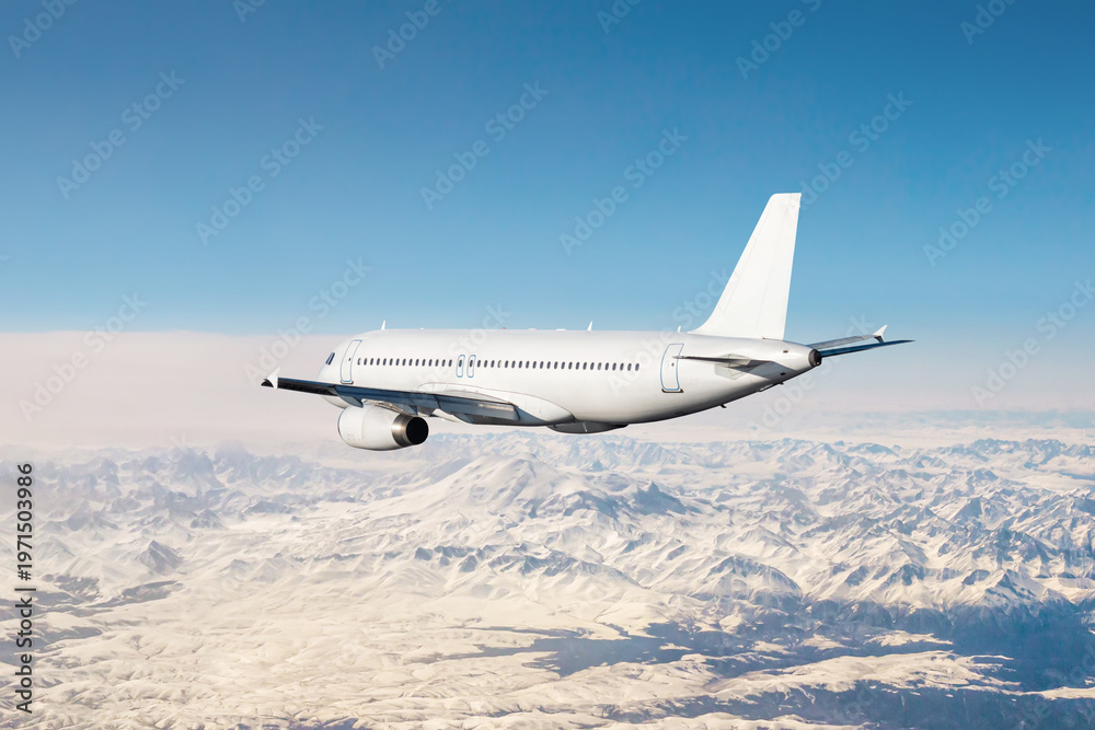 Obraz premium White modern airliner flies over snow covered mountains