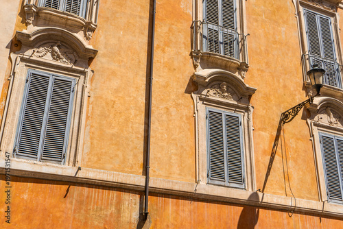 Italy Rome street orange house facade. Old historical building architecture in the city center. Italian window with shutters.