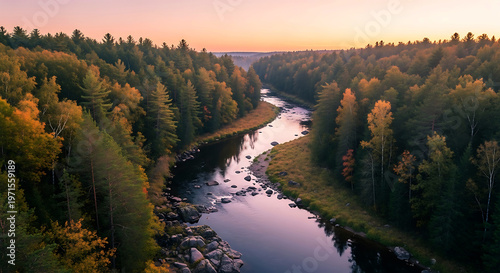 Aerial view of a winding river flowing through a dense autumn forest