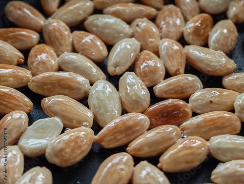 Close Up of Blanched Almonds Frying in Olive Oil in Black Pan Turning Golden Brown During Cooking