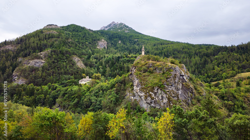 Naklejka premium Clocher Saint Julien de Méolans bell tower rising above a river, French Alps, Alpes-de-Haute-Provence, France, Europe.