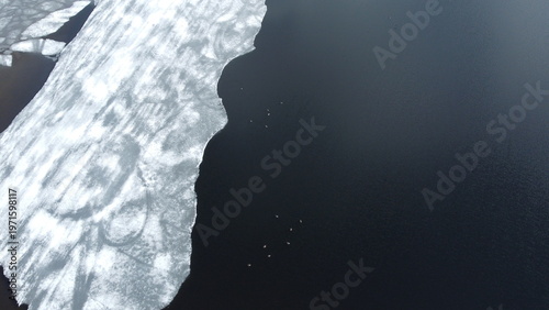 Ice and water meet in a frozen lake during early spring in the countryside