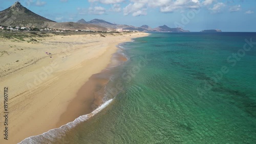 Aerial view of drone flying over golden sand beach with a small rock island in Porto Santo, Madeira, Portugal. Portuguese paradise with clean transparent water.