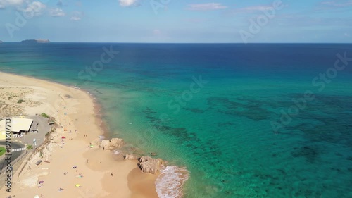 Aerial view of drone flying over golden sand beach with a small rock island in Porto Santo, Madeira, Portugal. Portuguese paradise with clean transparent water.