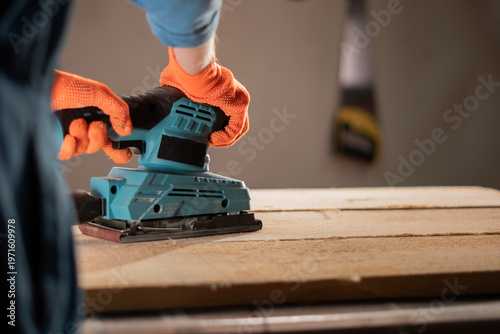 Photography carpenter hands with sander at workshop for polish