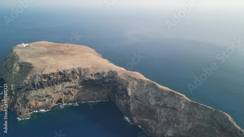 Aerial drone view over a rocky tiny island (Ilheu) with a light house. Volcanic scenic view in Porto Santo island, Madeira, Portugal