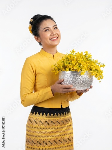 Burmese girl in traditional dress celebrating thingyan festival with padauk flowers
