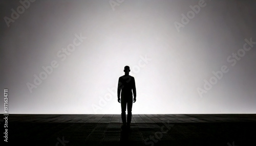 Silhouette of a man standing against a bright white background.