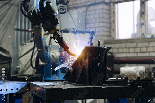 Robotic welding of metal with sparks in industrial workshop