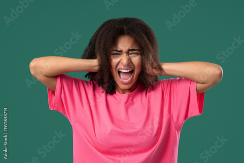 Angry woman yelling at camera with expressive face, covering ears with hands.