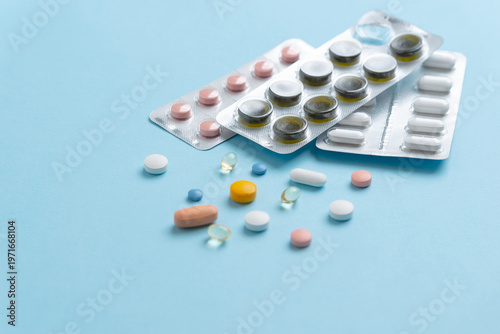 Close up of blister packs and colorful pills on blue background, pharmaceutical and medical concept
