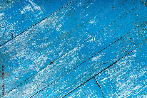 Close-up of weathered blue painted wooden planks with peeling layers, cracks and aged texture. Rustic surface ideal for vintage backgrounds and design use.