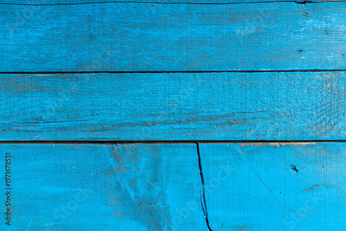 Close-up of weathered blue painted wooden planks with peeling layers, cracks and aged texture. Rustic surface ideal for vintage backgrounds and design use.