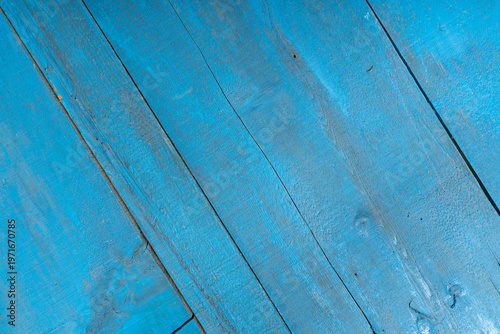 Close-up of weathered blue painted wooden planks with peeling layers, cracks and aged texture. Rustic surface ideal for vintage backgrounds and design use.
