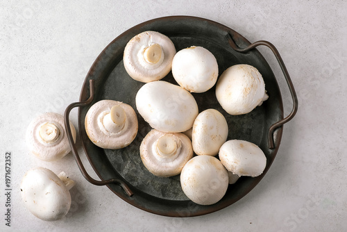 Top view of fresh white button mushrooms neatly arranged in a rustic iron pan on a light background. Perfect for cooking, recipes, or culinary-themed projects and ideas.